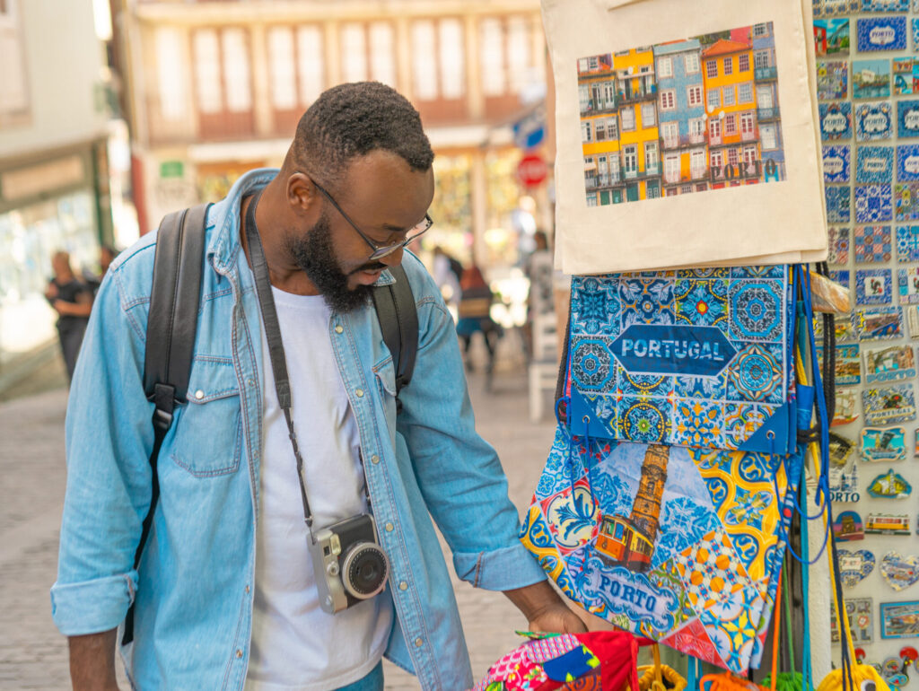 Living in Portugal as an American - traveller man with camera choosing the souvenirs at the typical souvenir shop. Travel in Portugal
